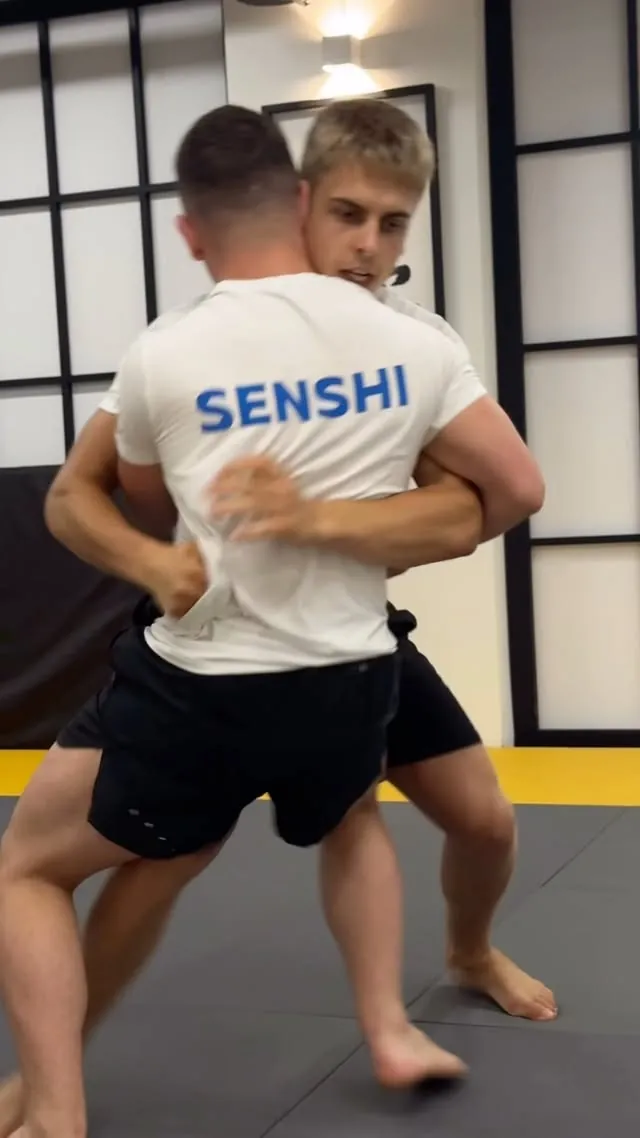 Clinch work in the dojo between two camp athletes, one in a SENSHI shirt